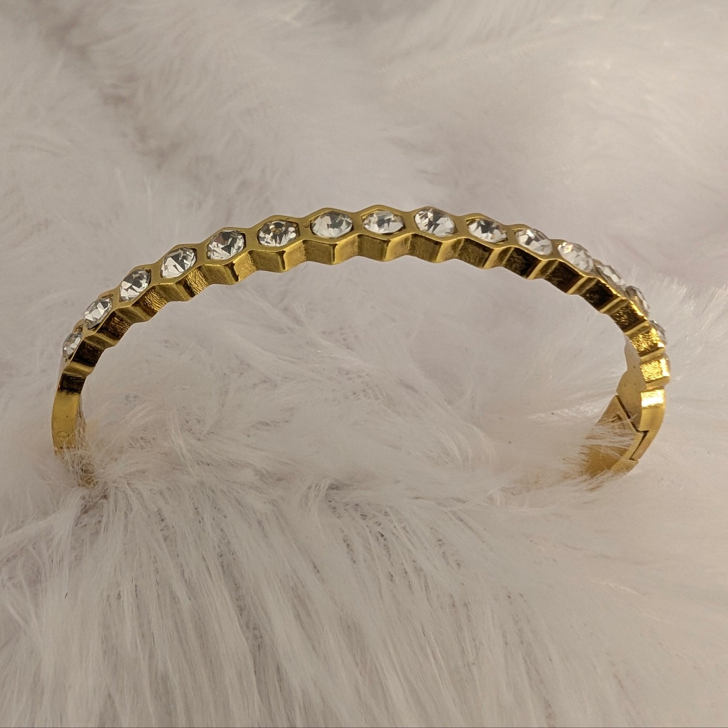 Gold bracelet with clear stones on a fluffy white surface