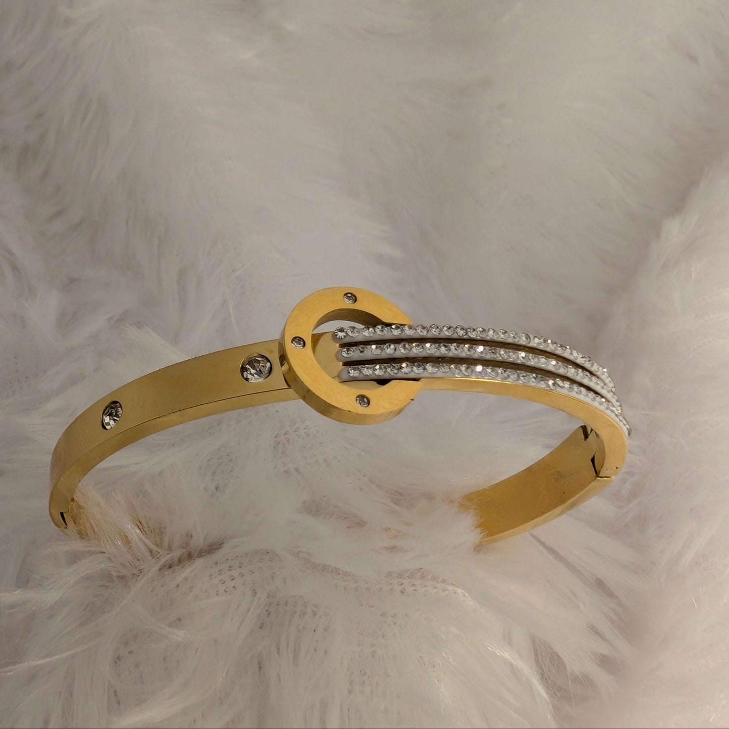Gold bracelet with diamond accents on a textured beige background