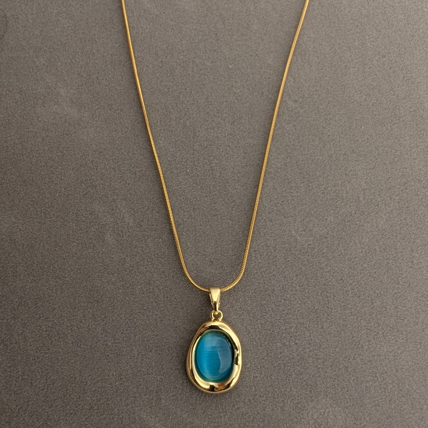Gold necklace with a blue pendant