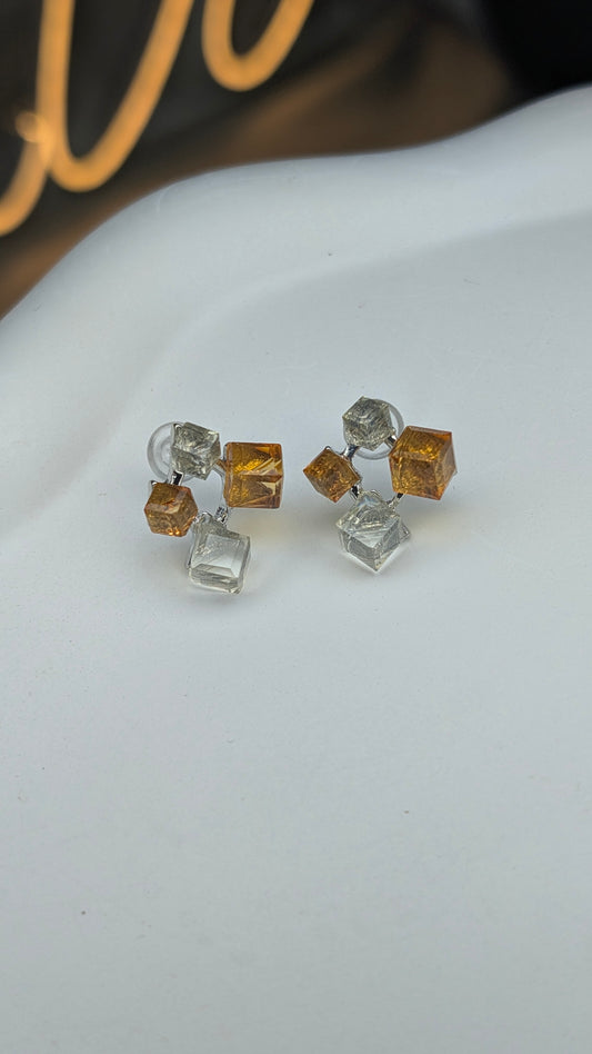 Pair of earrings with square-shaped crystals on a white surface