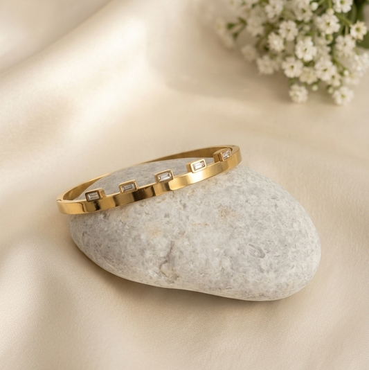 Gold bangle bracelet with small rectangular clear stones,