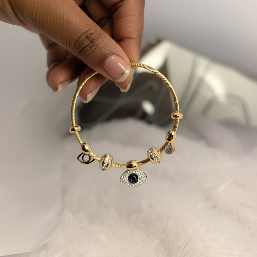 Gold bracelet with gemstones held by a hand on a white surface