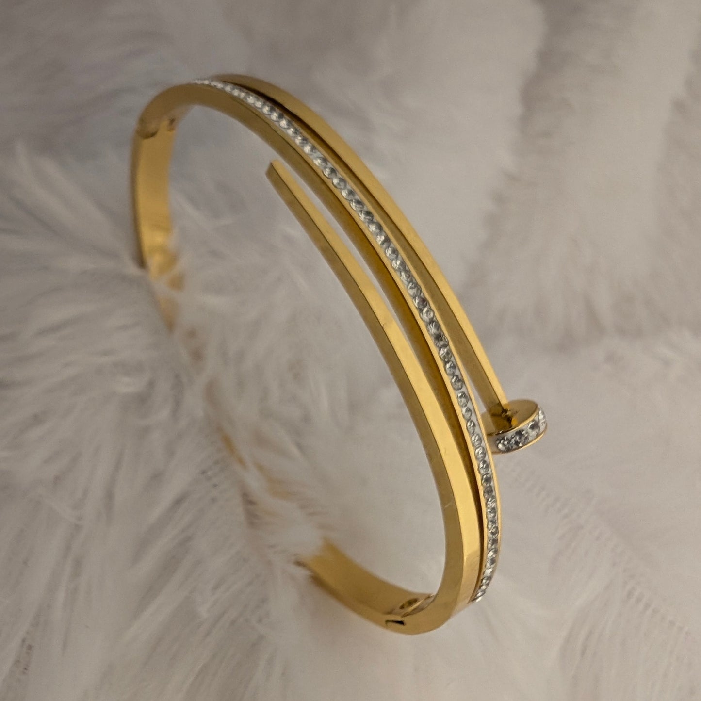 Gold bracelet with small diamonds on a textured white background