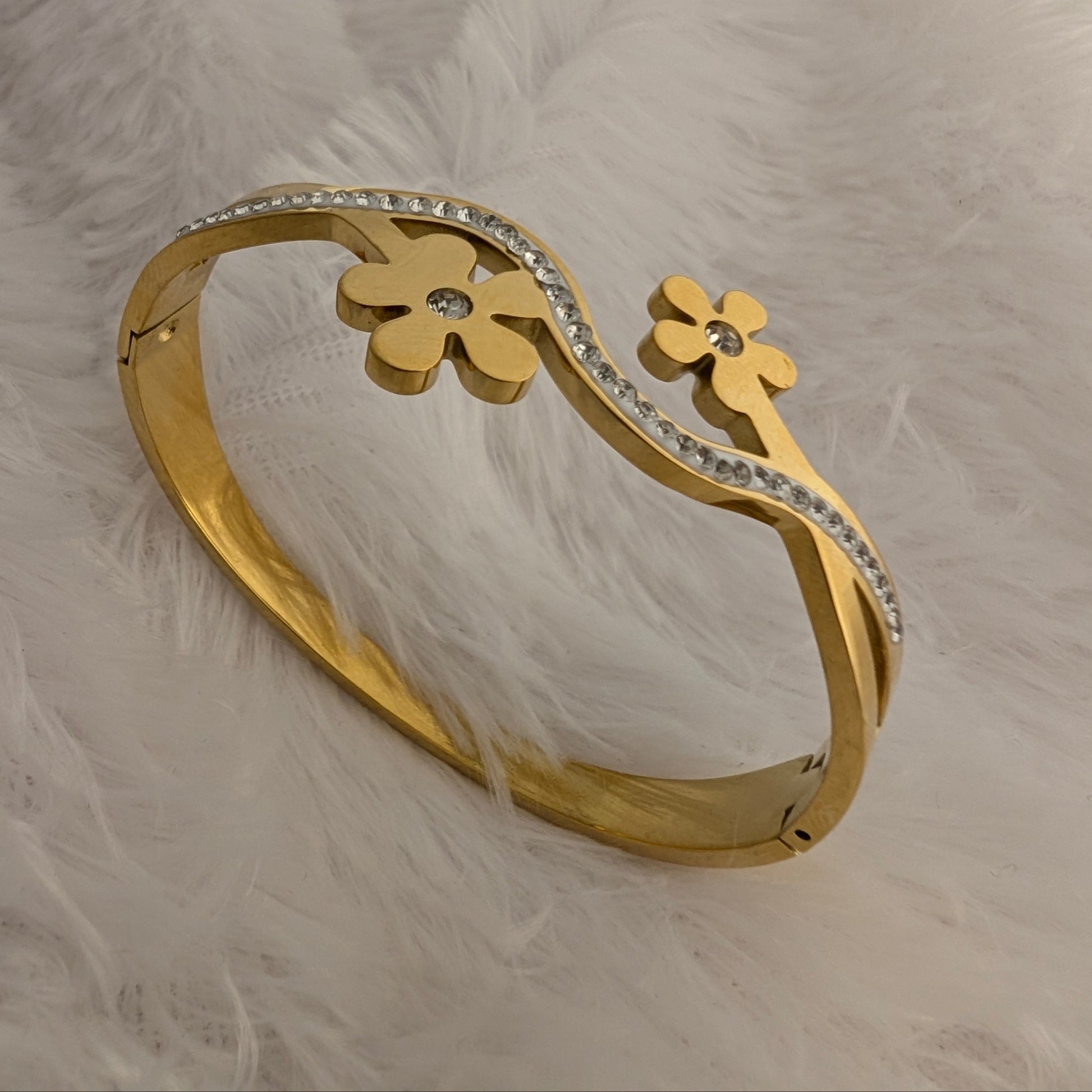 Gold bracelet with floral designs on a white fluffy background